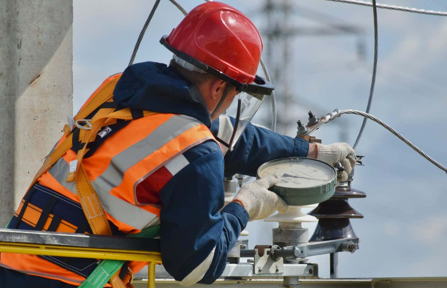 Güvenlik yelekli teknisyen dışarıda elektrikli ekipman ayarlıyor.
